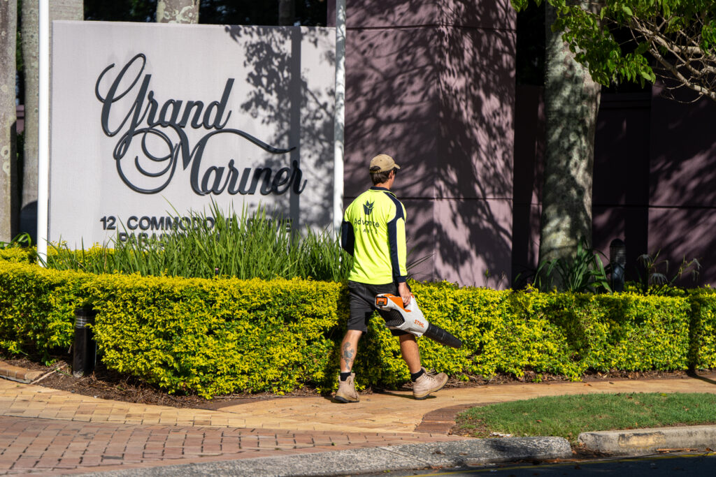 Advance Landscapes grounds maintenance team member at Grand Mariner entrance sign