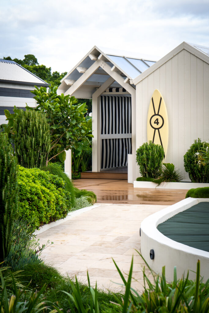White gabled poolside cabanas framed by clipped hedging and a curved stone path at QT Gold Coast, Surfers Paradise