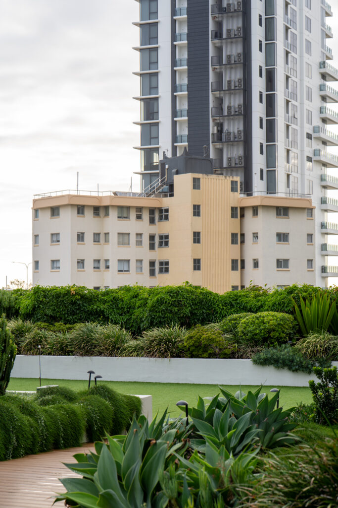 Podium lawn edged with agaves and tropical garden beds, apartment buildings behind, at QT Gold Coast, Surfers Paradise